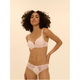 A woman modeling a light pink lace-trimmed bra and matching panties against a solid pale beige background.