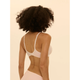 A woman with curly dark hair is shown from the back wearing a white underwire bra and a pale pink skirt against a solid cream background.
