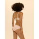 A woman with curly dark hair is shown from the back wearing a light pink two-piece lingerie set against a solid pale beige background.