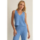 Woman wearing a blue ribbed sleeveless top and pants on a beige background