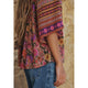 Person wearing a colorful floral and striped top against a stone wall background