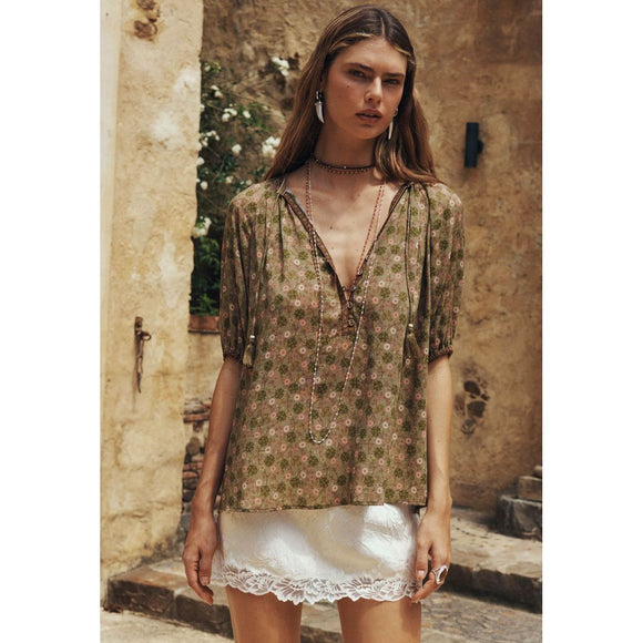 Woman wearing a floral blouse and white skirt in an outdoor setting