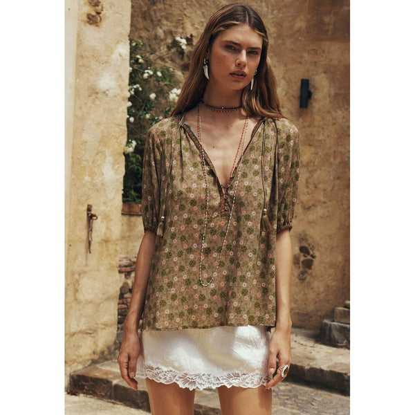 Woman wearing a floral blouse and white skirt in an outdoor setting