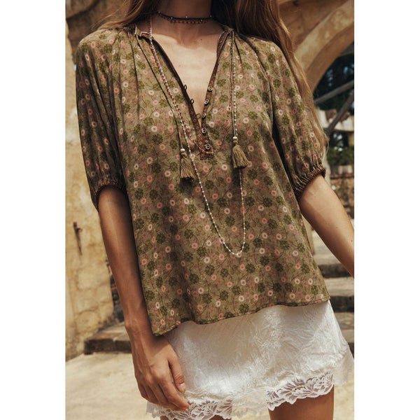 Woman wearing a floral blouse with tassels in an outdoor setting
