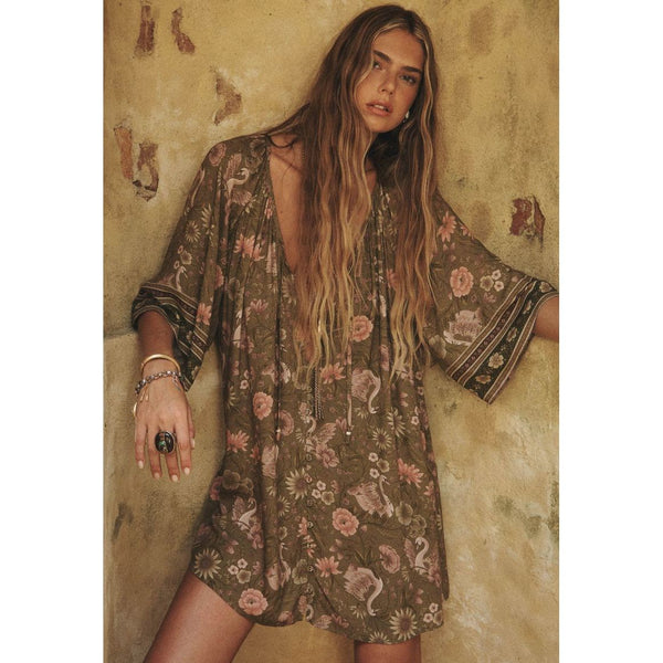Woman wearing a floral dress against a textured wall.