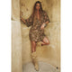 Woman in a floral dress and beige boots leaning against a textured wall.