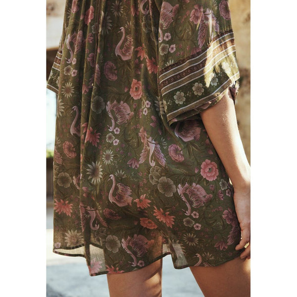 Person wearing a floral dress with a pattern of swans and flowers.