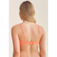 Woman wearing an orange bikini top against a beige background