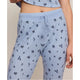 A close-up of a person wearing light blue waffle-knit pajama pants with a small dark floral print and a matching drawstring waist, paired with a matching cropped top.
