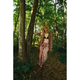 Woman in a patterned sarong and jacket standing in a forest