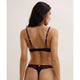 Woman wearing a dark brown lingerie set on a beige background