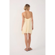 Woman wearing a low back light yellow dress with thin straps on a white background
