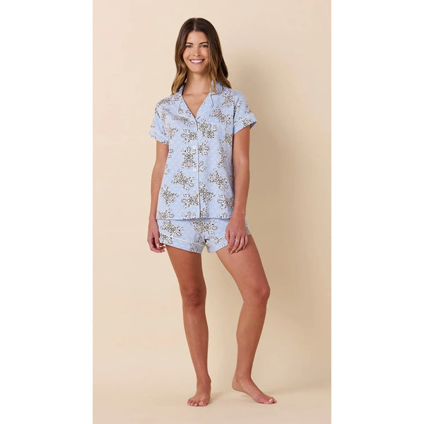 Woman wearing a light blue pajama set with a floral pattern on a beige background
