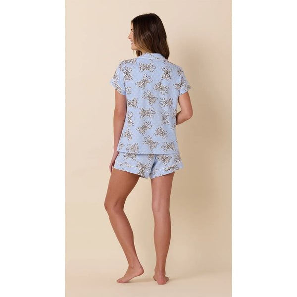 Woman wearing a light blue pajama set with a butterfly pattern on a beige background