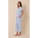 A woman modeling a light blue pajama set with a delicate beige floral pattern, standing against a solid beige background.