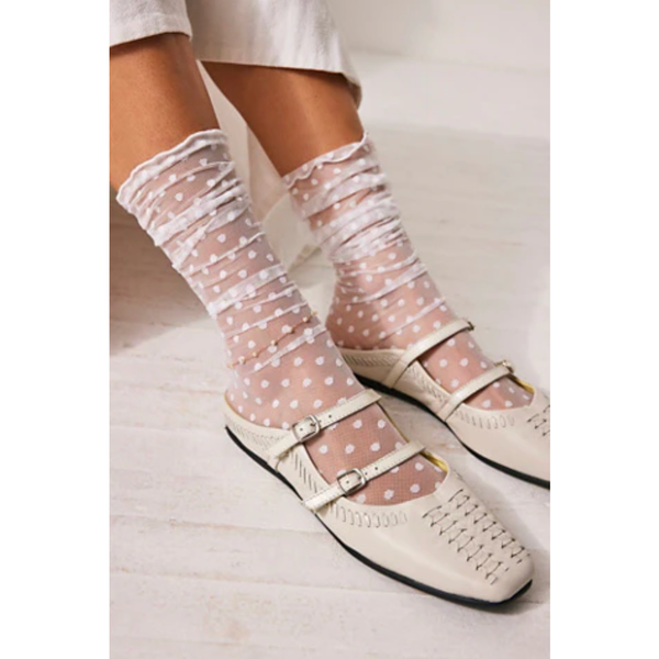 White shoes with polka dot sheer socks on a light background