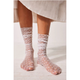Sheer socks with white polka dots worn by a person on a light wooden floor.