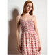 Woman wearing a floral dress against a white wall