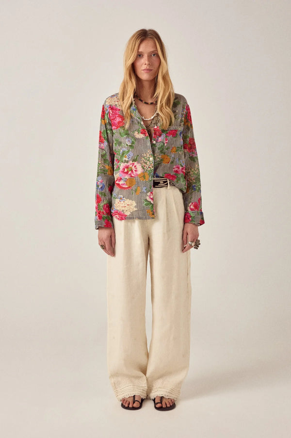 Woman wearing a floral shirt and beige pants on a white background