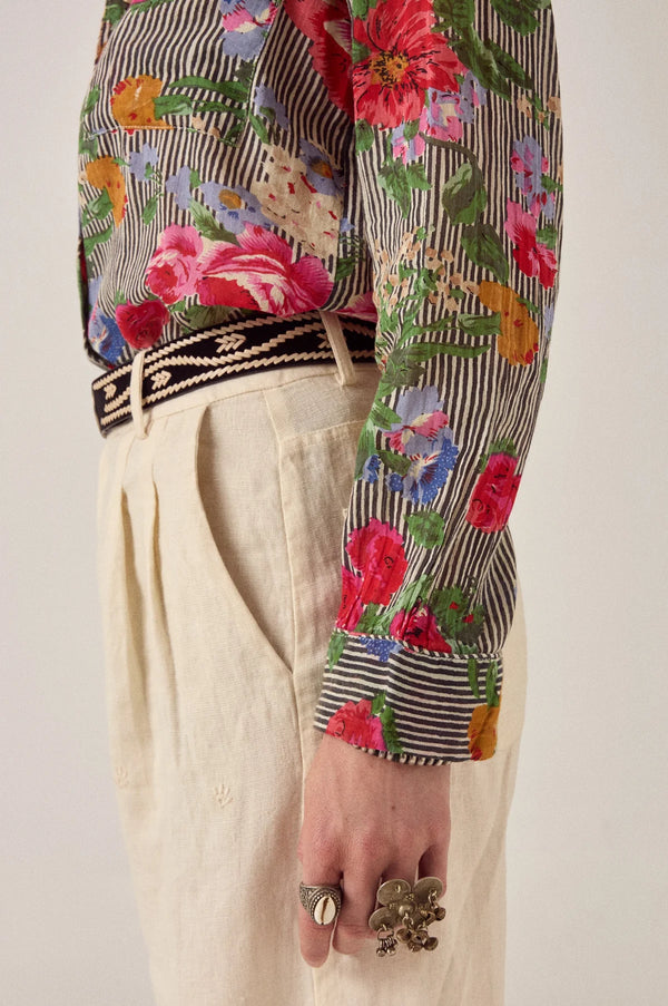 Close-up of a person wearing a colorful floral shirt  with a plain background