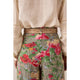 Floral patterned pants with a beige shirt and decorative belt.