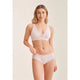 Woman wearing a light pink bra and underwear set on a plain background