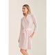 Woman wearing a light pink robe on a beige background