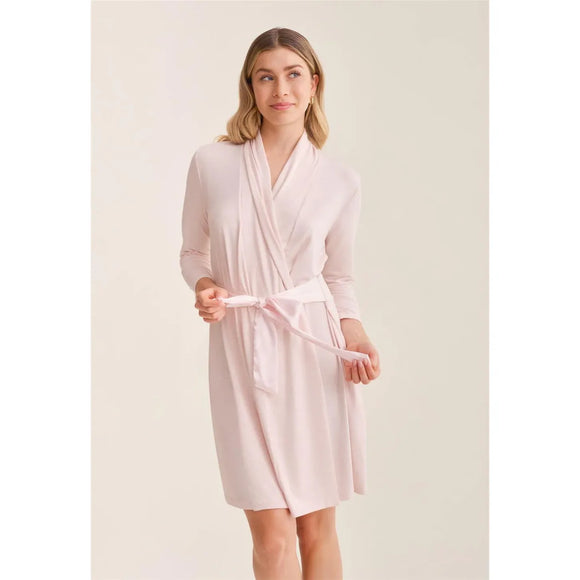 Woman wearing a light pink robe against a plain background