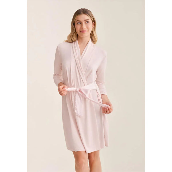 Woman wearing a light pink robe against a plain background