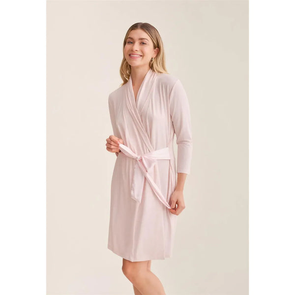 Woman wearing a light pink robe against a plain background