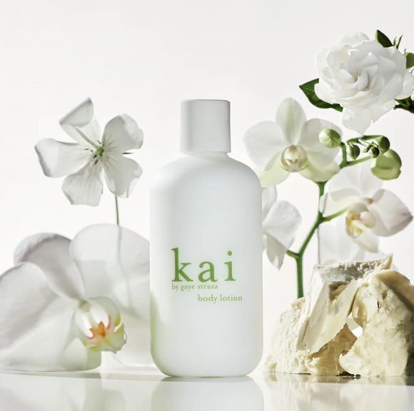 White 'kai' body lotion bottle surrounded by white flowers on a light background