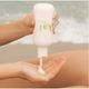 Person applying kai body cream from a 'kai' bottle with a beach background