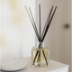 Clear kai diffuser bottle with black sticks on a white surface