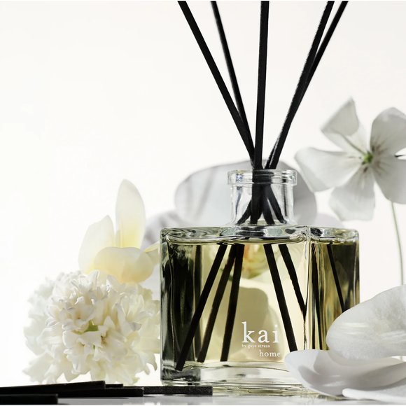 Diffuser with black sticks surrounded by white flowers on a light background