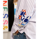 Person wearing a colorful 'LOVE' shirt over a striped shirt with a blurred background.