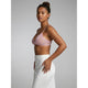 A woman modeling a light pink sheer mesh bralette with white polka dots, paired with a white skirt, against a solid gray studio background.