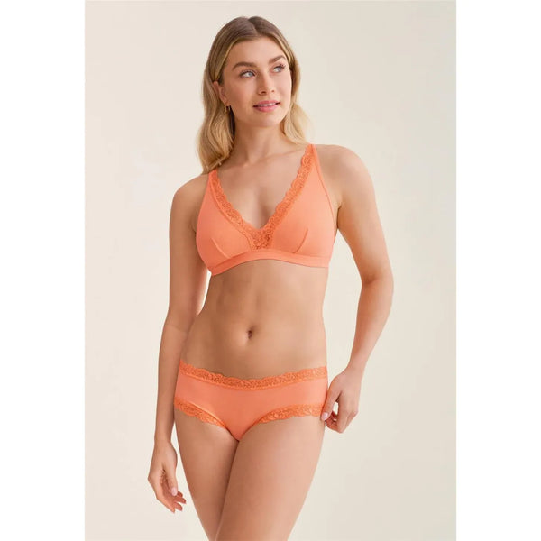Woman wearing an orange lingerie set on a beige background