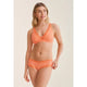 Woman wearing an orange lingerie set on a beige background