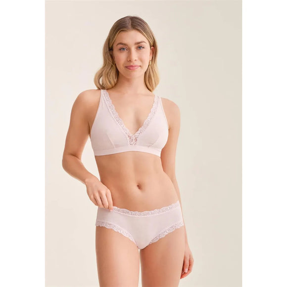 Woman wearing a white lace bra and panties set on a beige background