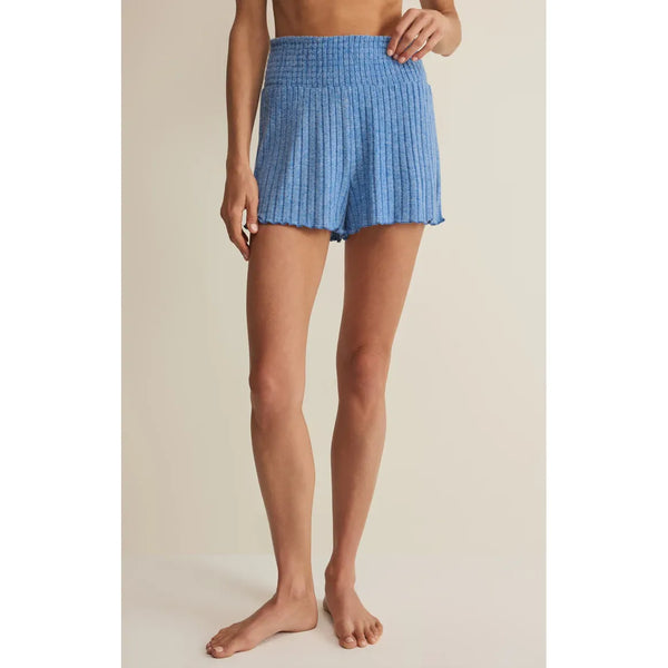 Person wearing blue checkered shorts on a beige background